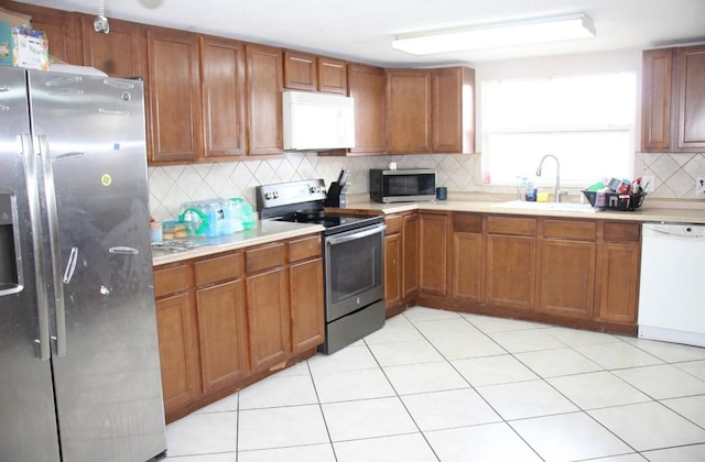 7204 Westcott Dr, Port Richey, FL 34668 - kitchen featuring stainless steel appliances, a sink, tasteful backsplash, light countertops, and brown cabinetry