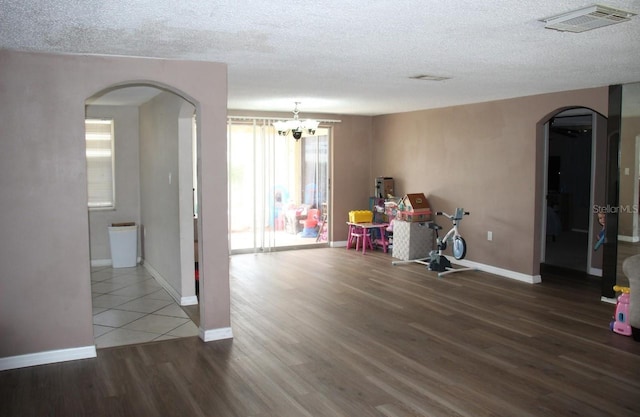7204 Westcott Dr, Port Richey, FL 34668 - recreation room featuring arched walkways, a textured ceiling, wood finished floors, baseboards, and a chandelier