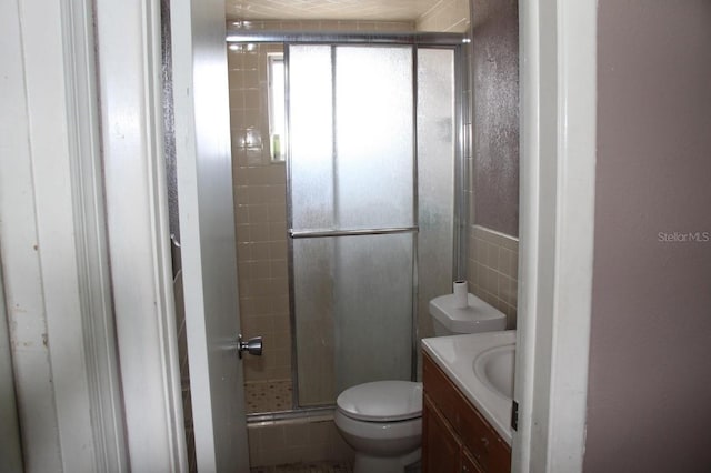 bathroom featuring toilet, a shower with shower door, and vanity