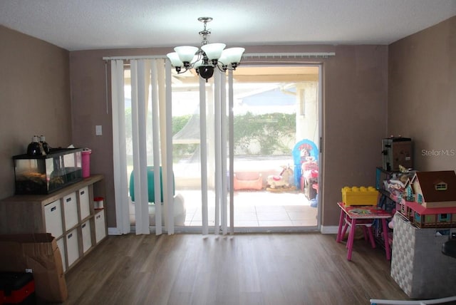 playroom with a notable chandelier, a textured ceiling, and wood-type flooring