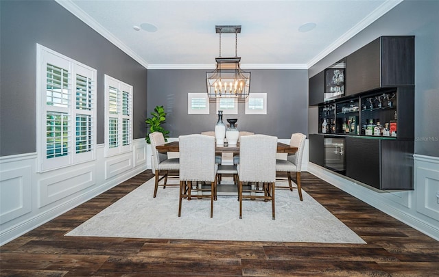 dining area featuring crown molding, bar, an inviting chandelier, and dark hardwood / wood-style flooring