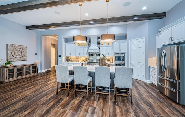 kitchen featuring an island with sink, hanging light fixtures, white cabinetry, stainless steel appliances, and premium range hood