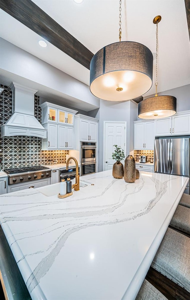 kitchen with white cabinetry, backsplash, decorative light fixtures, and custom exhaust hood