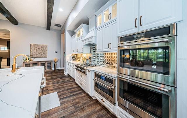 kitchen featuring appliances with stainless steel finishes, beamed ceiling, white cabinets, and light stone counters