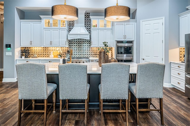 kitchen with premium range hood, hanging light fixtures, dark hardwood / wood-style floors, and white cabinets