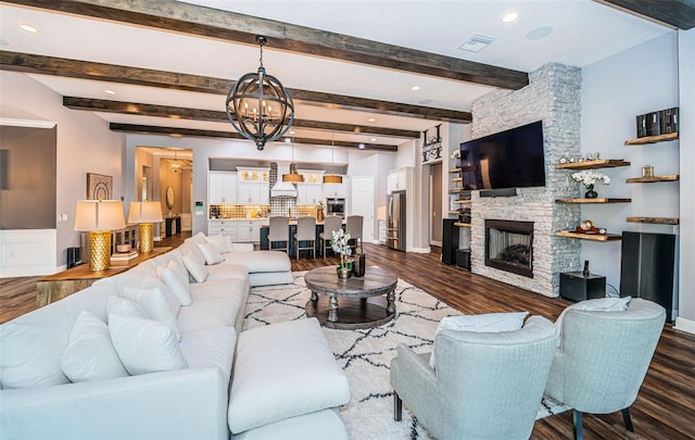 living room with a notable chandelier, dark hardwood / wood-style floors, beamed ceiling, and a fireplace