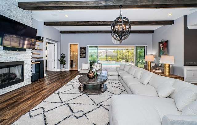 living room with hardwood / wood-style flooring, beamed ceiling, an inviting chandelier, and a fireplace