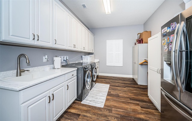 laundry area featuring dark wood-type flooring, washing machine and dryer, sink, and cabinets