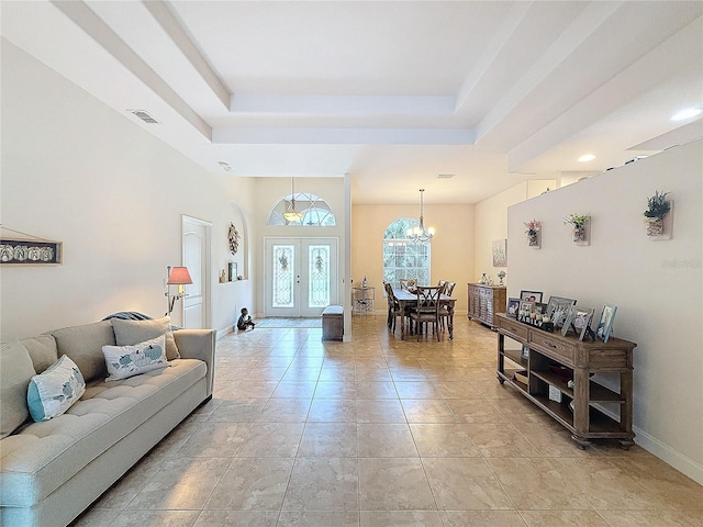 tiled living room with french doors, a tray ceiling, and an inviting chandelier