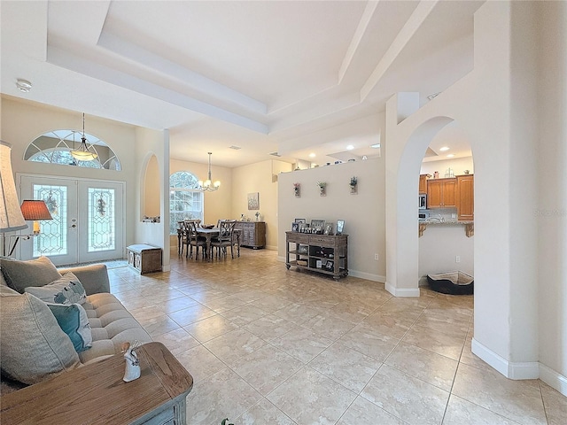 living room with a chandelier, french doors, and a tray ceiling