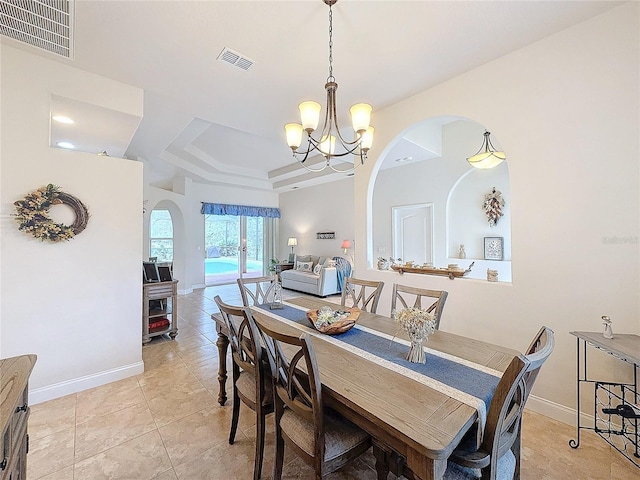 tiled dining room with a raised ceiling and a notable chandelier