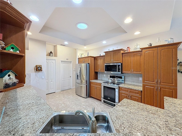 kitchen featuring stainless steel appliances, tasteful backsplash, a tray ceiling, and sink