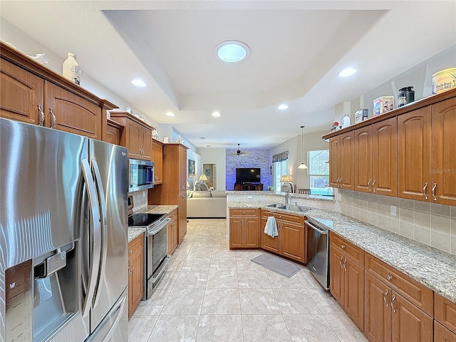 kitchen featuring decorative backsplash, light stone countertops, stainless steel appliances, ceiling fan, and hanging light fixtures