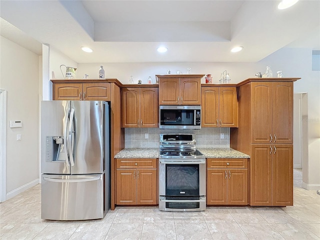 kitchen with backsplash, light tile patterned flooring, light stone counters, and stainless steel appliances