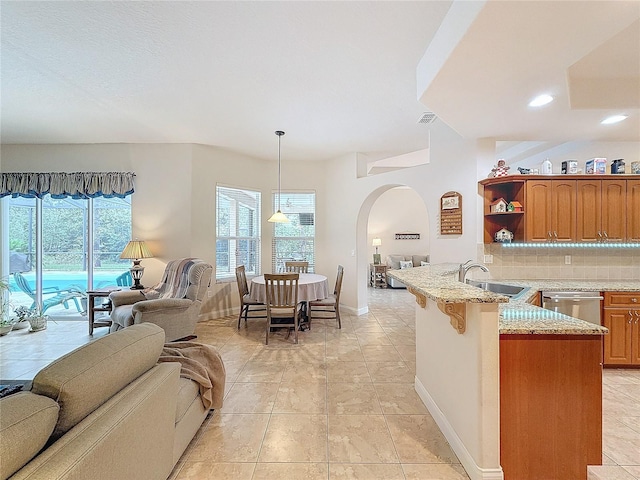 kitchen with sink, hanging light fixtures, tasteful backsplash, kitchen peninsula, and a breakfast bar area