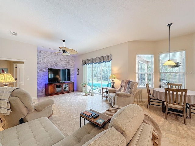 tiled living room featuring ceiling fan and a textured ceiling