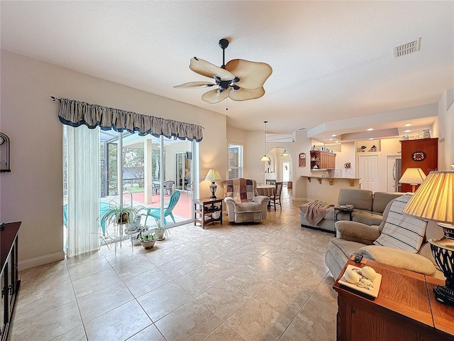 living room featuring ceiling fan, light tile patterned floors, and a textured ceiling