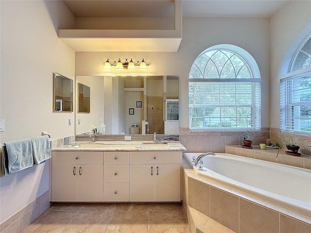 bathroom with vanity, a relaxing tiled tub, and tile patterned floors