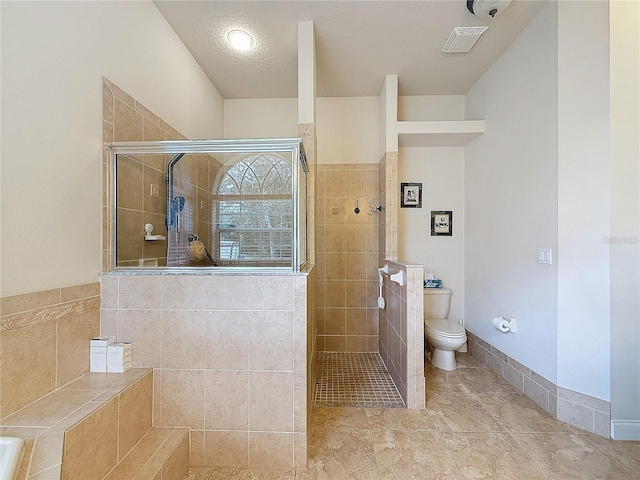 bathroom featuring tiled shower, a textured ceiling, and toilet