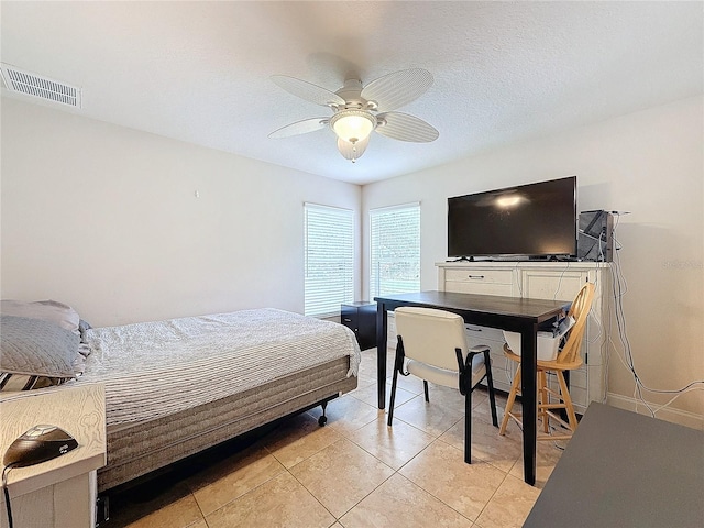 bedroom with ceiling fan, light tile patterned flooring, and a textured ceiling