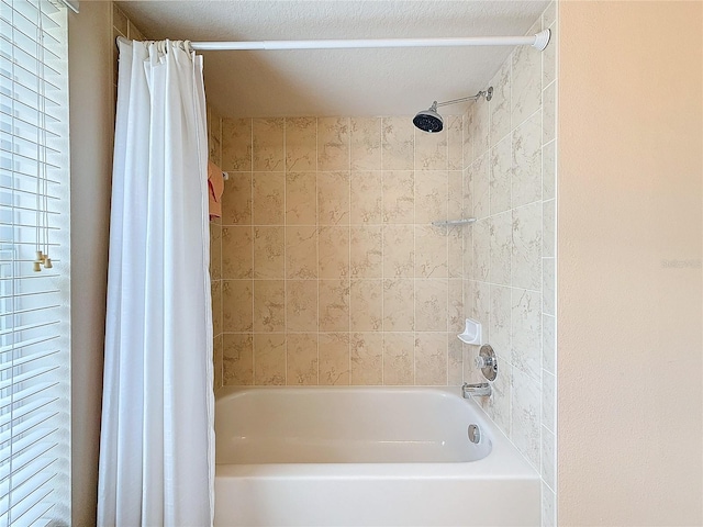 bathroom with shower / tub combo with curtain and a textured ceiling