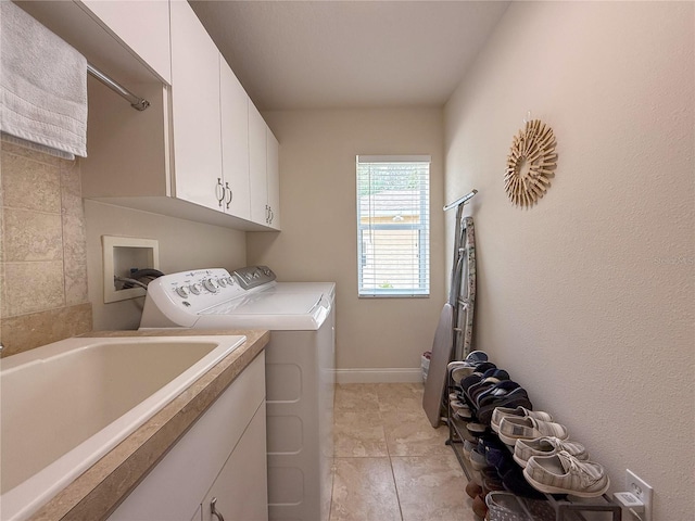 laundry area with cabinets, light tile patterned floors, washing machine and dryer, and sink