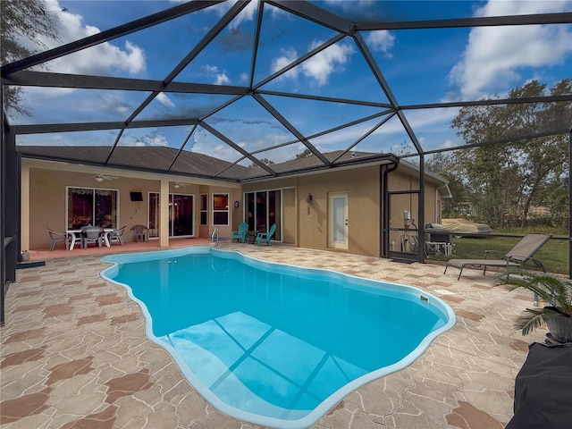 view of swimming pool with a patio, glass enclosure, and ceiling fan