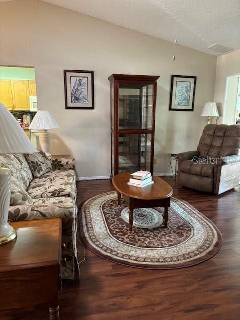 living room featuring a textured ceiling, dark wood-type flooring, and vaulted ceiling