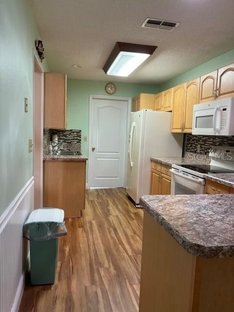 kitchen with white appliances, light hardwood / wood-style floors, backsplash, and light brown cabinets