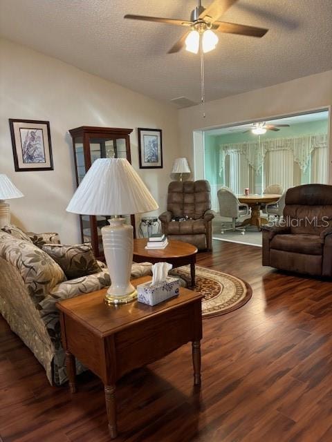 living room featuring a textured ceiling, dark wood-type flooring, and ceiling fan