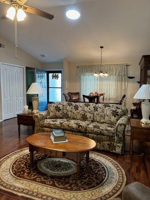 living room featuring ceiling fan with notable chandelier, vaulted ceiling, and dark hardwood / wood-style floors