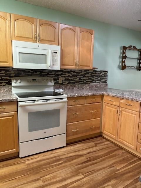 kitchen with white appliances, decorative backsplash, a textured ceiling, and light wood-type flooring