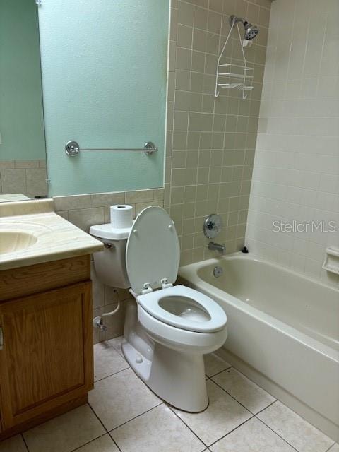 full bathroom featuring tiled shower / bath, vanity, toilet, and tile walls