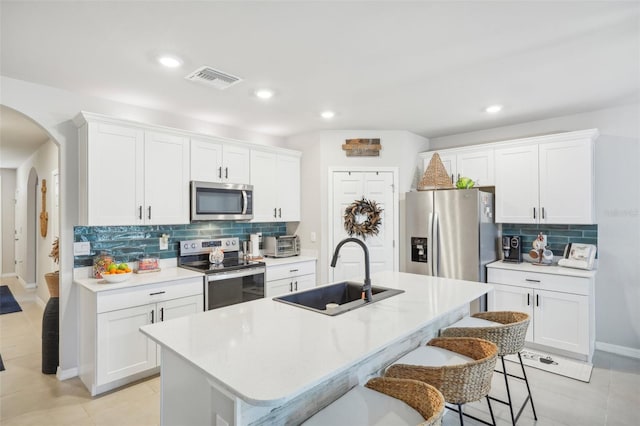 kitchen featuring appliances with stainless steel finishes, white cabinets, sink, and a center island with sink