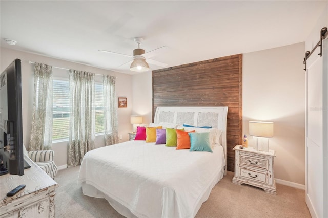 bedroom featuring wood walls, a barn door, light colored carpet, and ceiling fan