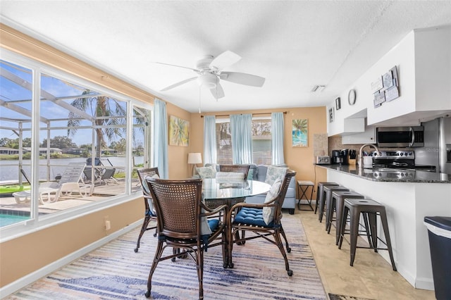 dining space with a textured ceiling, a healthy amount of sunlight, light tile patterned floors, and ceiling fan