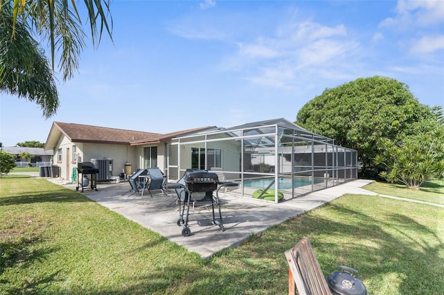 back of property with a patio, glass enclosure, and a yard