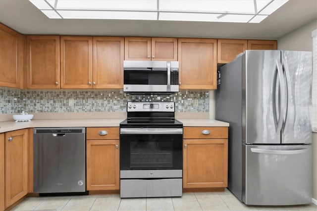 kitchen with appliances with stainless steel finishes, tasteful backsplash, and light tile patterned floors