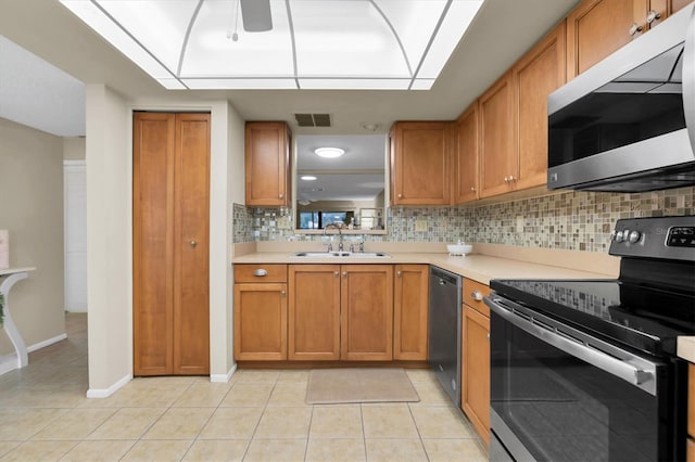 kitchen featuring backsplash, appliances with stainless steel finishes, sink, and light tile patterned floors