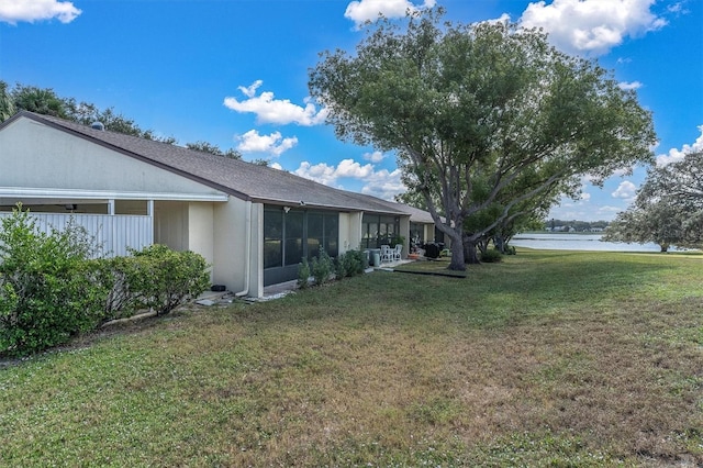 view of yard with a sunroom and a water view