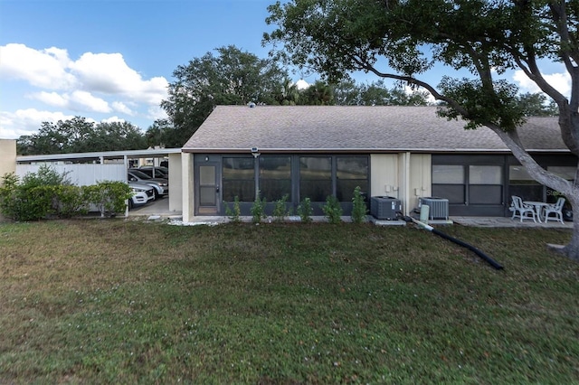 back of house featuring central air condition unit, a yard, and a sunroom