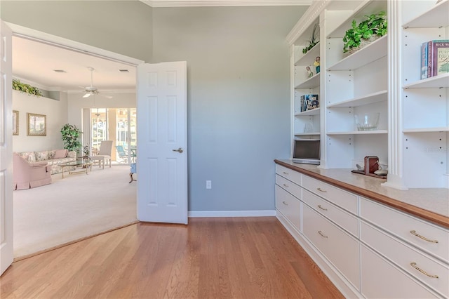 interior space featuring crown molding, white cabinetry, light wood-type flooring, and ceiling fan