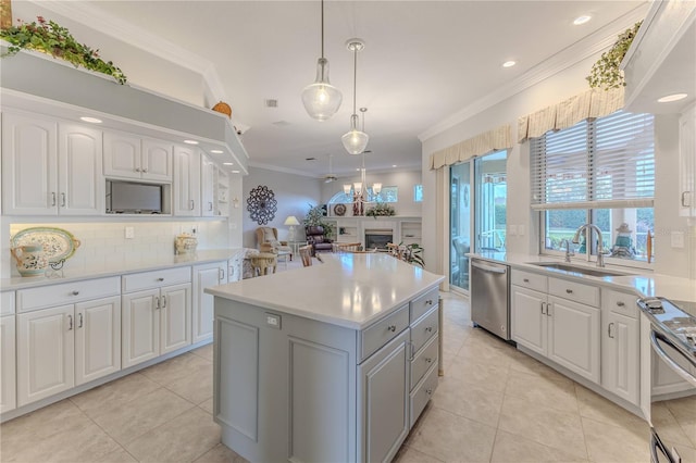 kitchen with appliances with stainless steel finishes, a kitchen island, hanging light fixtures, white cabinetry, and crown molding