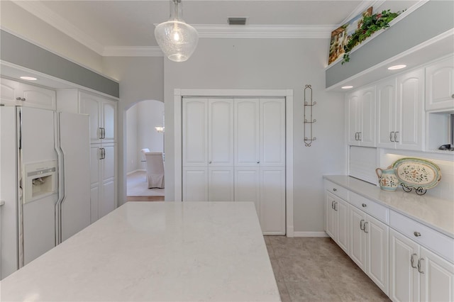 kitchen featuring crown molding, white cabinetry, hanging light fixtures, and white fridge with ice dispenser