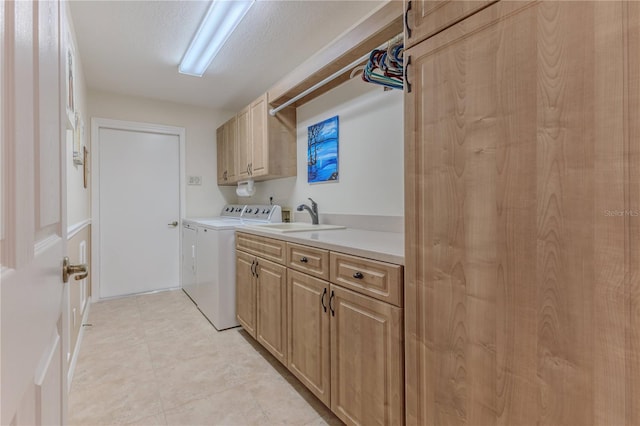 laundry room featuring sink, washing machine and dryer, a textured ceiling, and cabinets