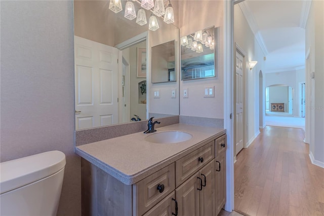 bathroom with vanity, ornamental molding, hardwood / wood-style flooring, and toilet