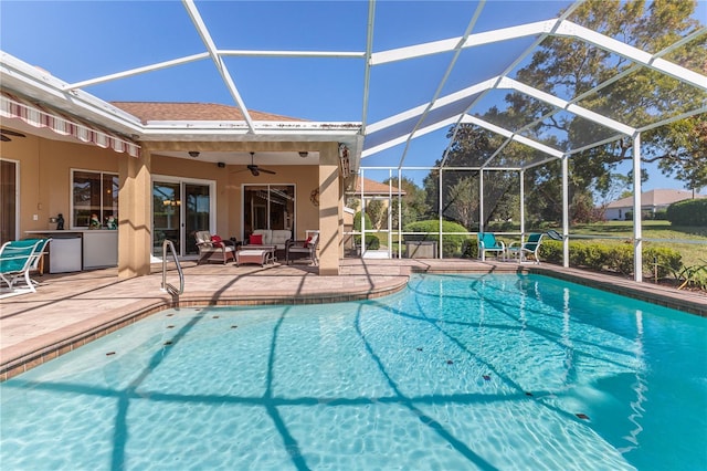 view of pool with a patio, glass enclosure, and ceiling fan