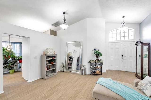 entrance foyer featuring a notable chandelier, high vaulted ceiling, and light hardwood / wood-style flooring