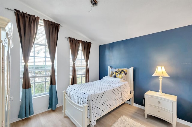 bedroom featuring vaulted ceiling and light wood-type flooring