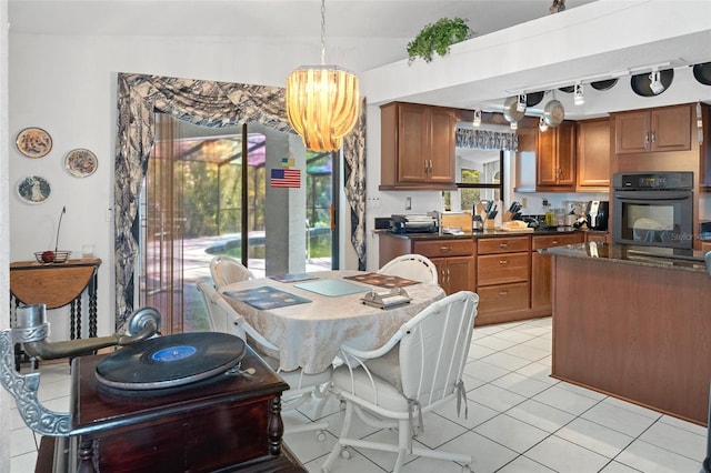 kitchen with oven, light tile patterned flooring, hanging light fixtures, rail lighting, and vaulted ceiling